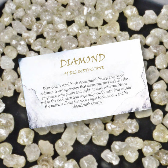 Card about diamond as April birthstone on a background of raw diamonds